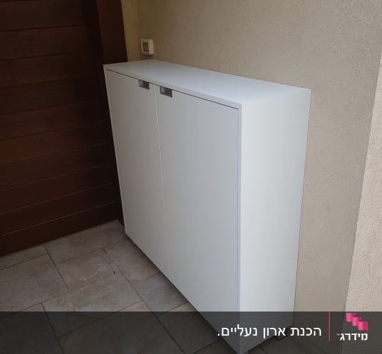 ארון לבן עם דלתות סגורות על רצפת אריחים